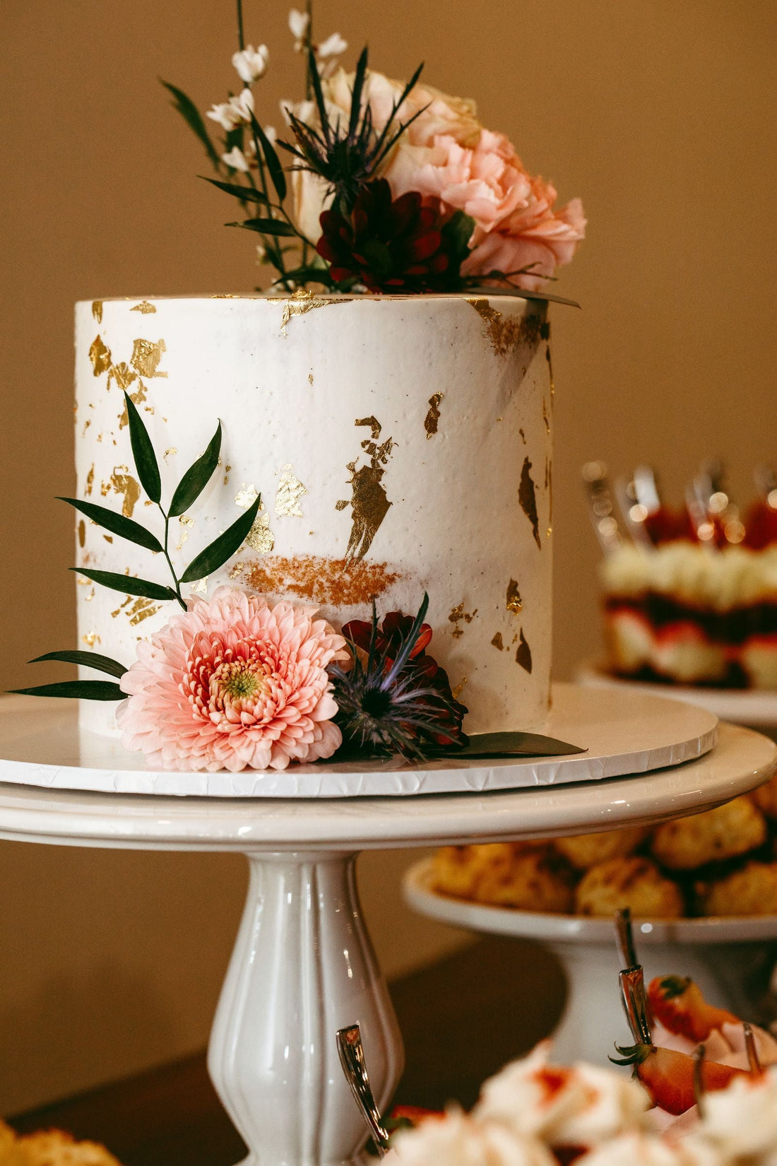 Wedding cake with fresh flowers and gold accents; editorial inspiration photo, not a Rosy Flower Wall product or client event.