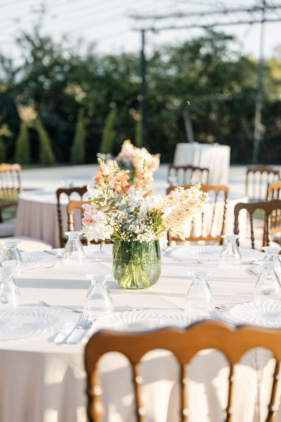 Outdoor wedding table arranged with flowers, plates, and glassware