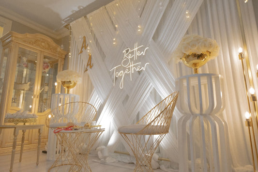 Indoor wedding backdrop with flowers, lights, and chairs