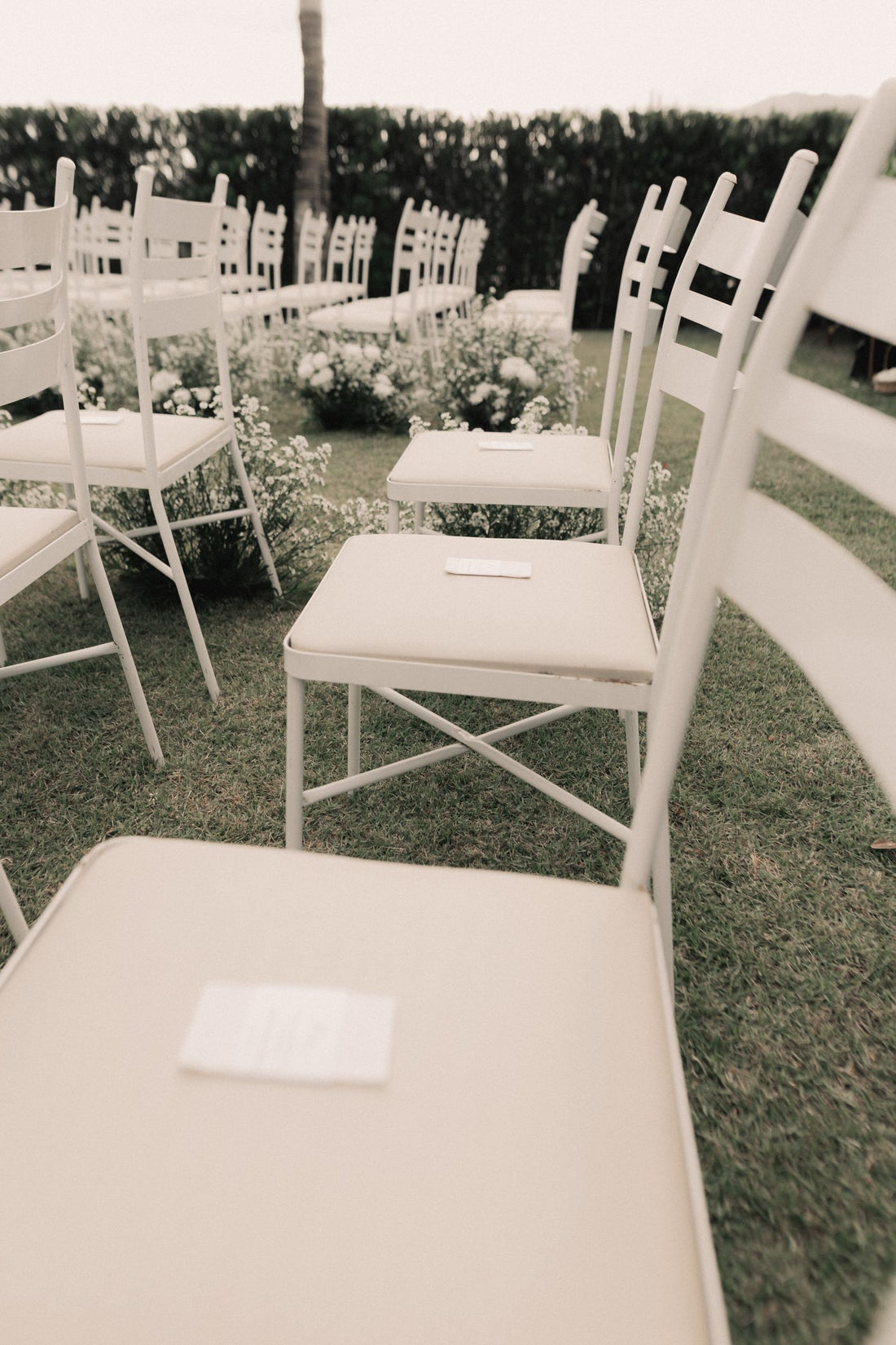 Outdoor wedding ceremony chairs with white floral decorations along the aisle