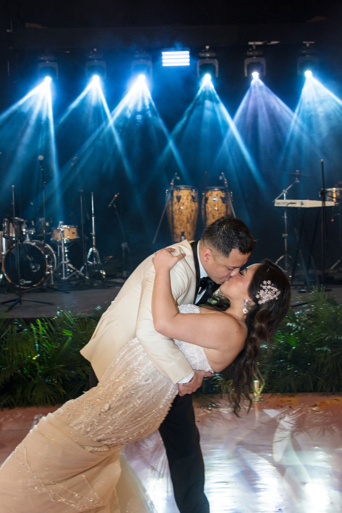 Couple dancing at a wedding reception under colorful stage lights
