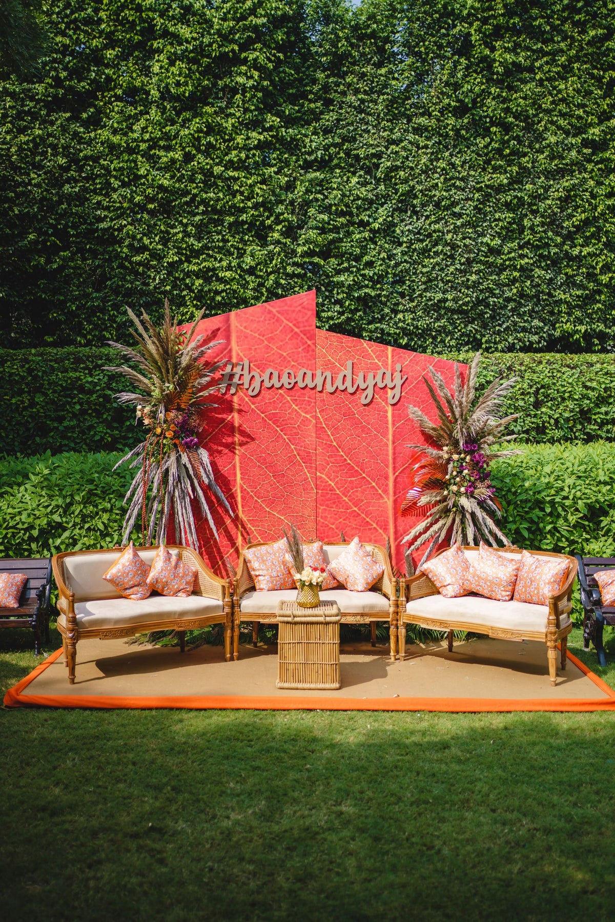 Outdoor wedding lounge with floral backdrop, chairs and colorful cushions