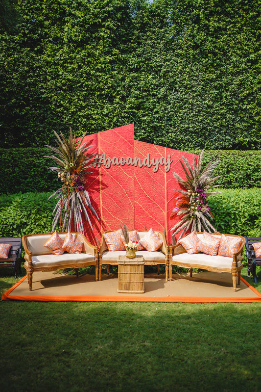 Outdoor wedding lounge with floral backdrop, chairs and colorful cushions