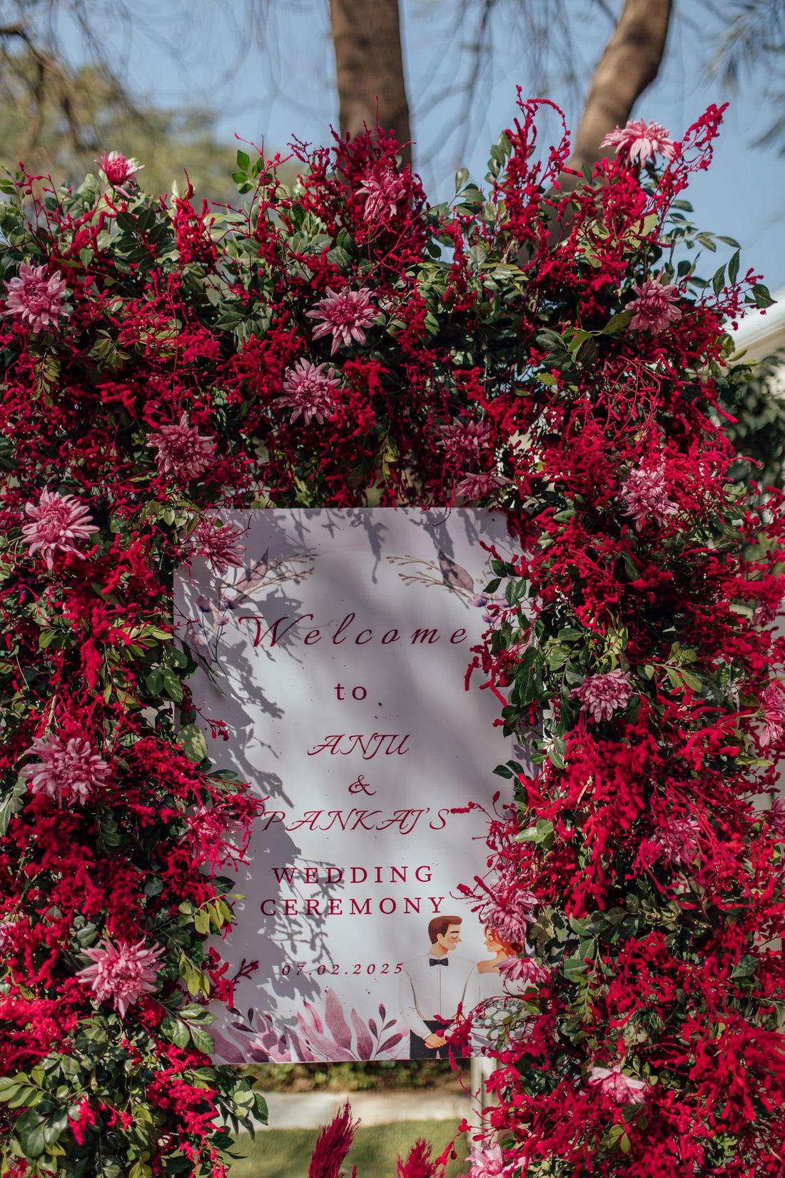 Floral wedding welcome sign with red flower accents outdoors