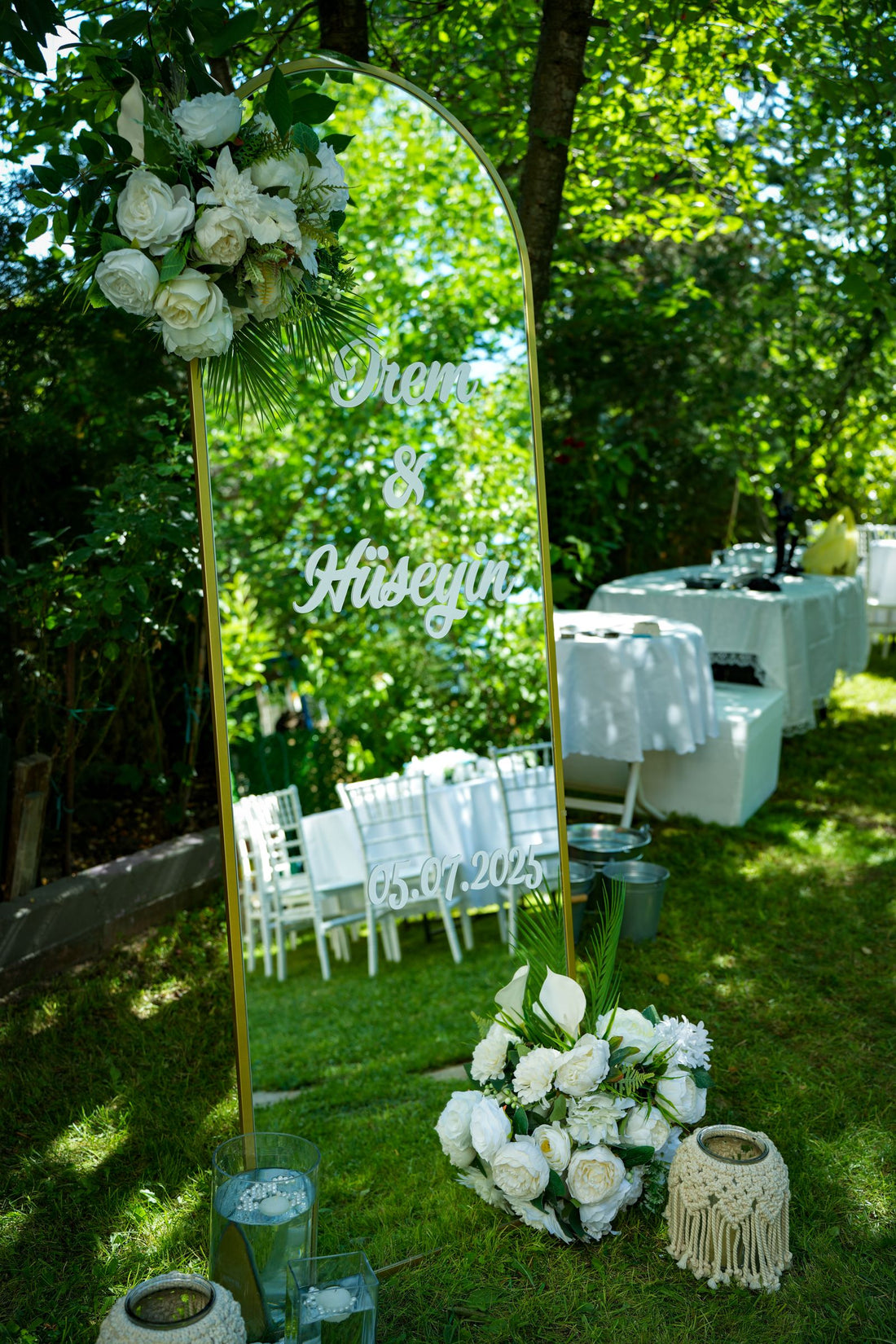 Outdoor wedding setup with floral decor, white chairs, and a mirror