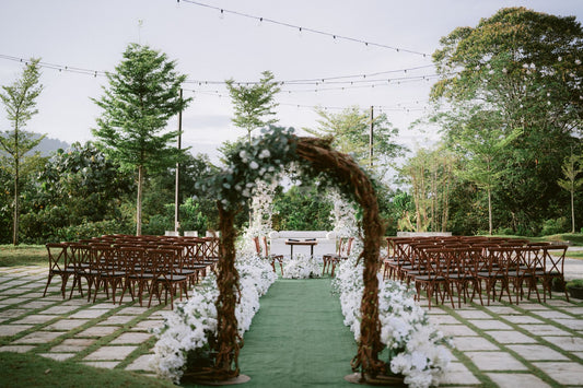 Outdoor ceremony setup with a floral arch, chairs, and aisle