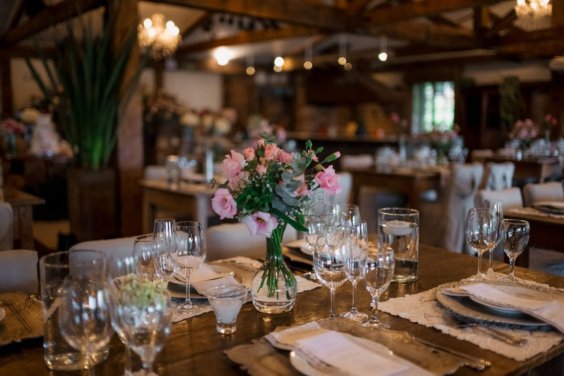 A wedding table with a floral centerpiece, glassware, and soft lighting
