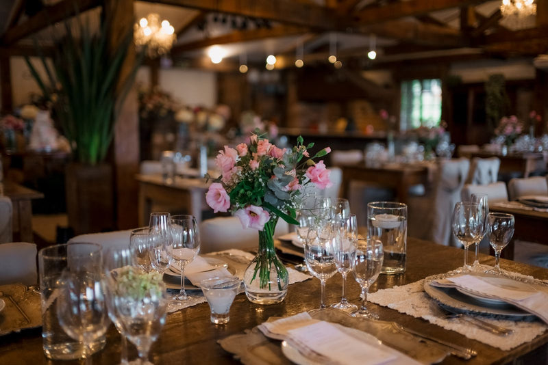 A wedding table with a floral centerpiece, glassware, and soft lighting
