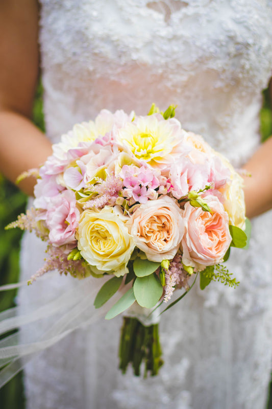 Close-up of a bride holding a bouquet with roses and lilies