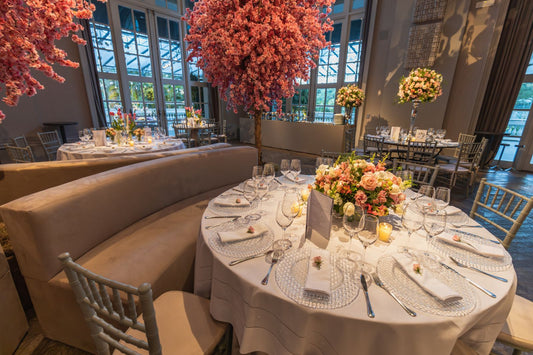 Wedding reception room with round tables, floral centerpieces, table settings, and warm ambient lighting