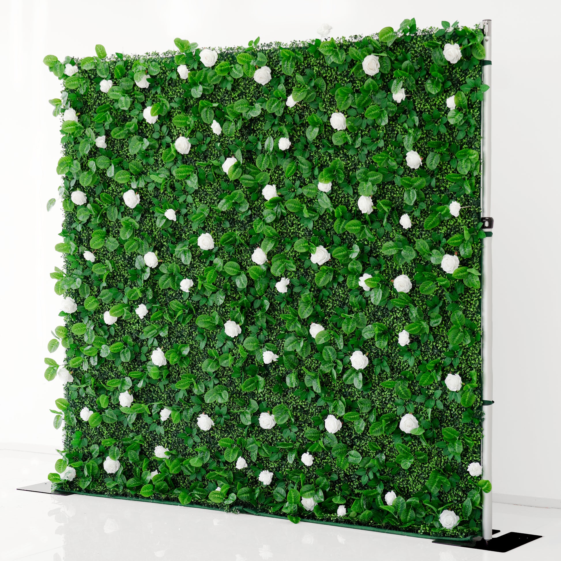 Artificial green wall with white flowers on a stand against a white background