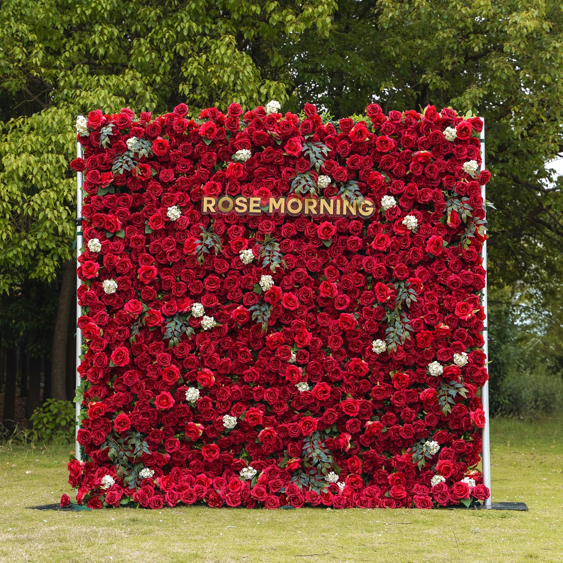 Red artificial rose wall backdrop with green foliage