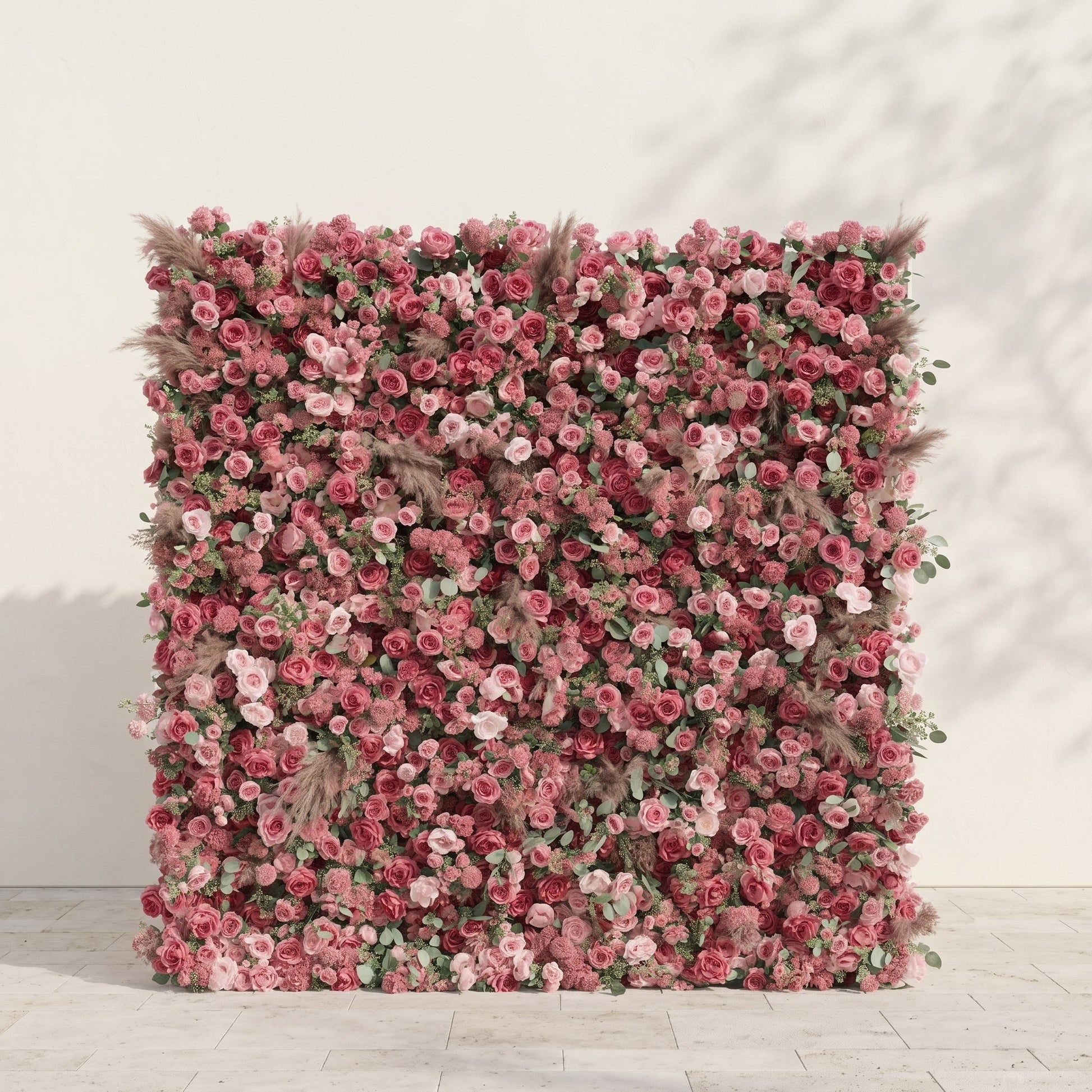 Dusty rose and nude pink silk flower wall on a warm white studio background