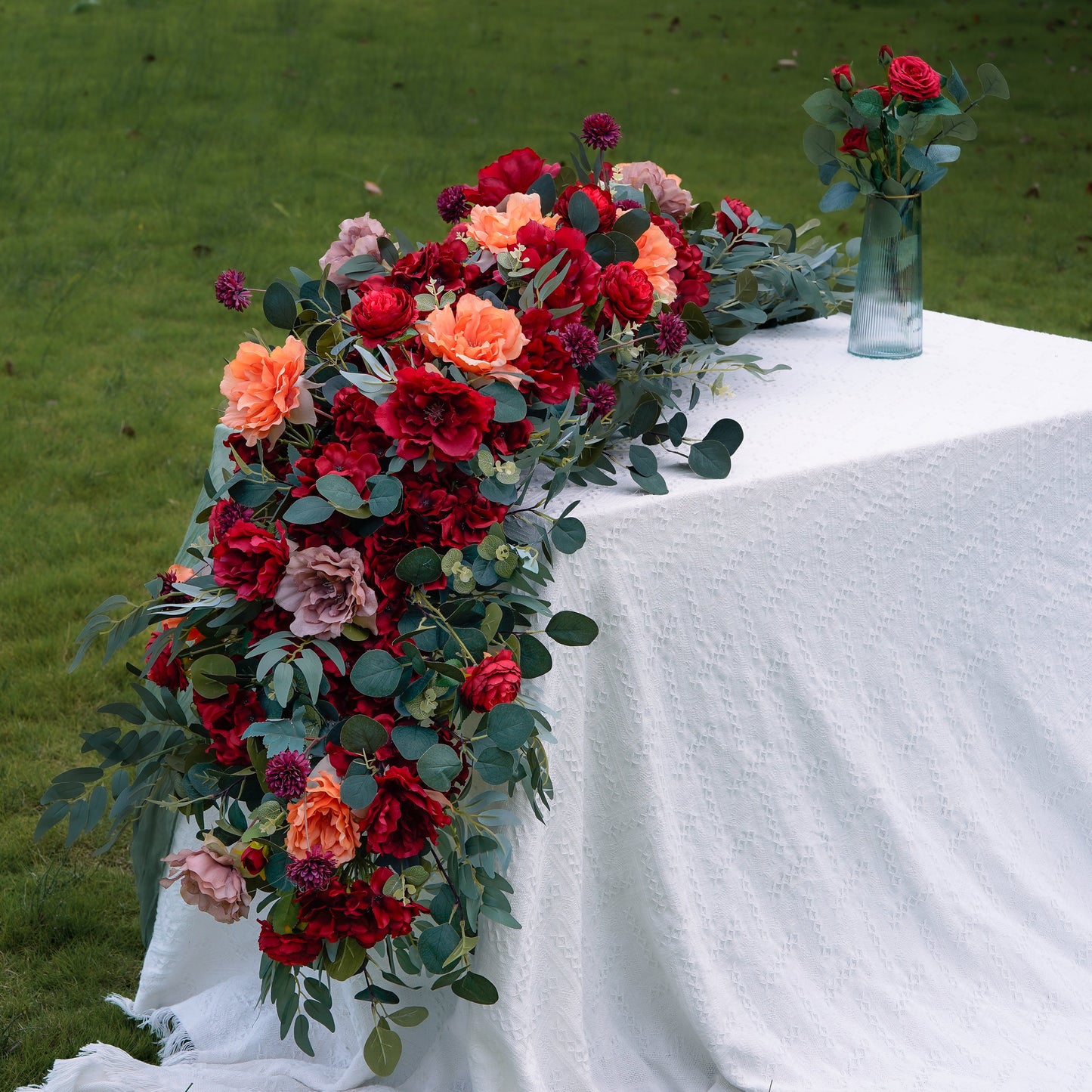 Red burgundy and coral artificial flower runner styled on a long table
