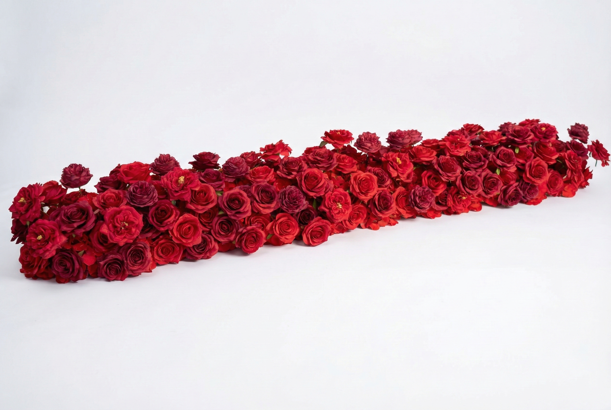 Long red rose artificial flower runner on a warm white studio background