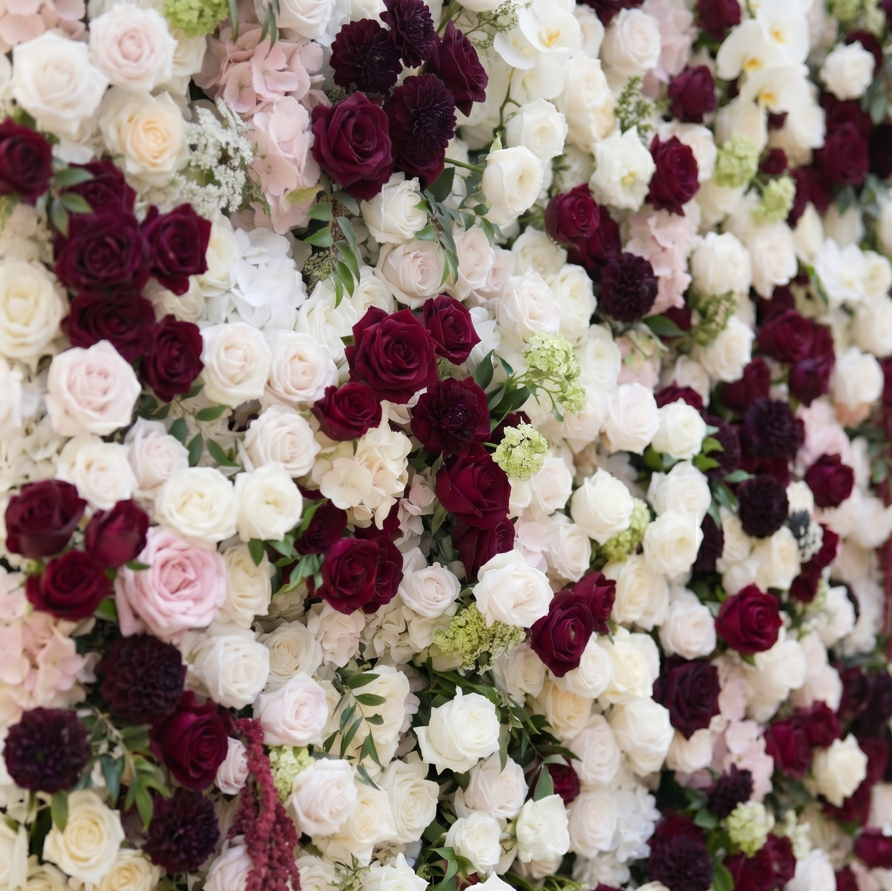 Close-up detail of burgundy roses ivory flowers blush hydrangeas and greenery